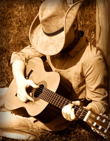 41009834 - cowboy  plays guitar on ranch .country music